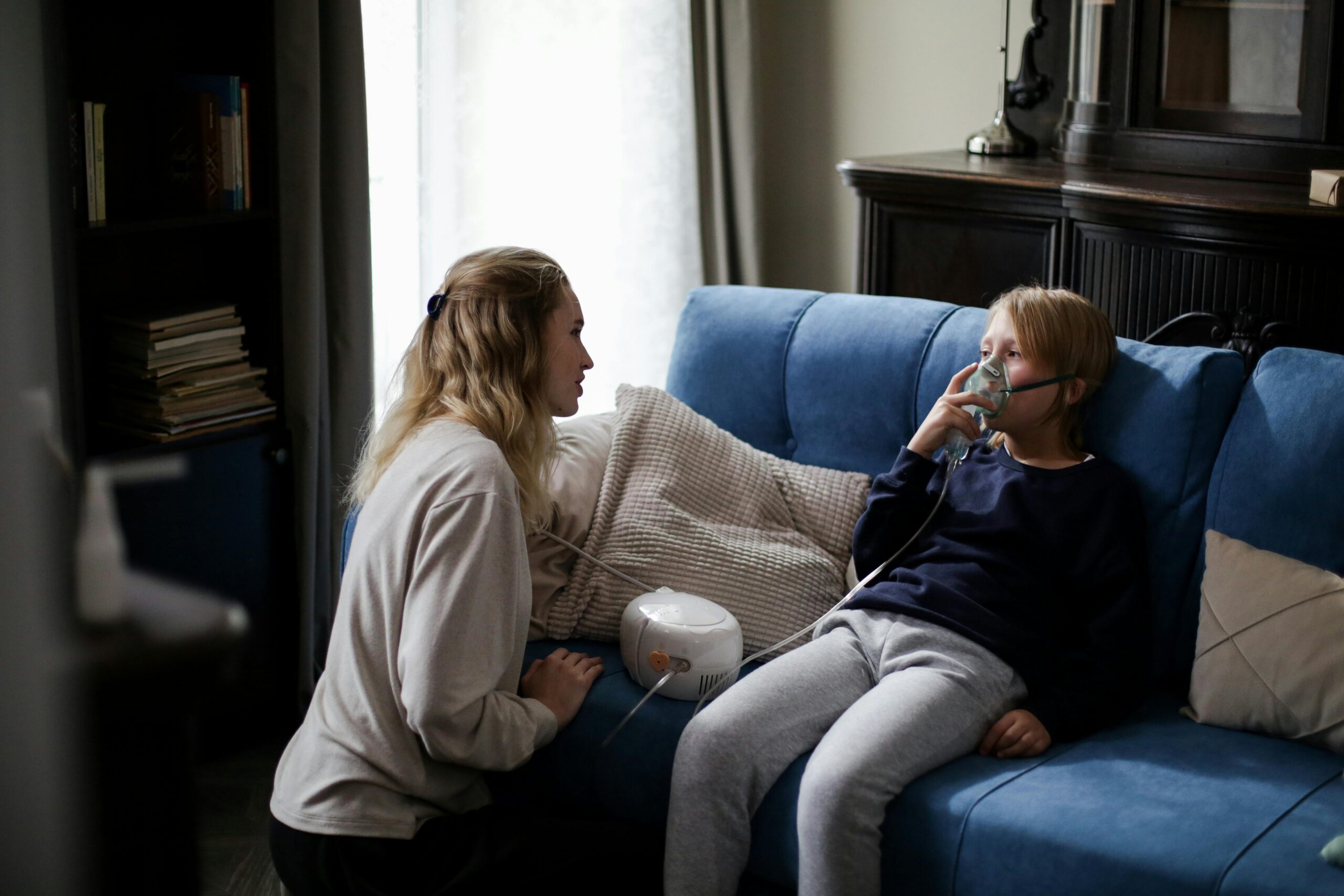 A mother helping her child use a respiratory mask indoors, highlighting the chronic respiratory challenges faced by many children today due to poor indoor air quality.