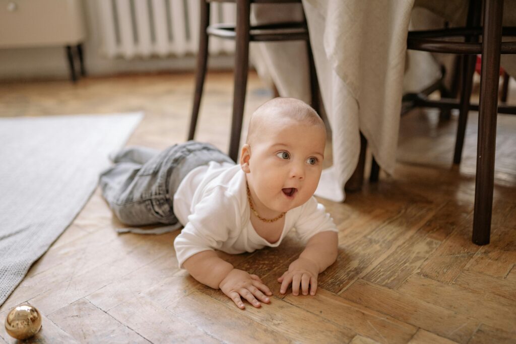 Infant crawling on a wooden floor, highlighting the vulnerability of young children to toxic dust and environmental pollutants during early development.