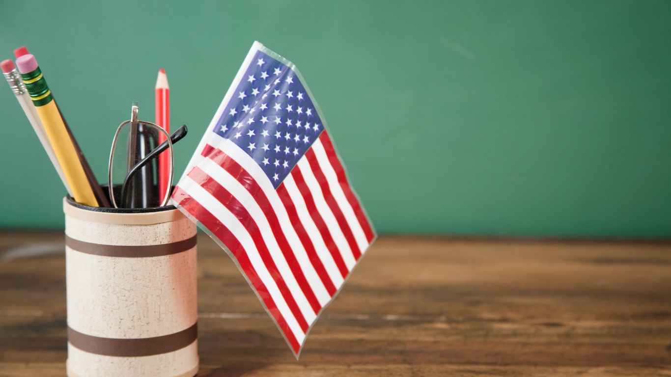 Pencil cup and American flag on a desk in front of a green chalkboard