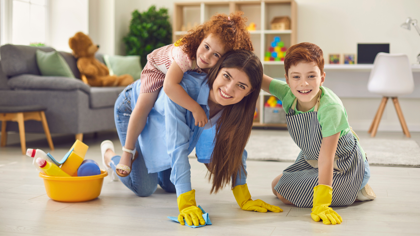 Mother and two children smiling while cleaning the living room floor